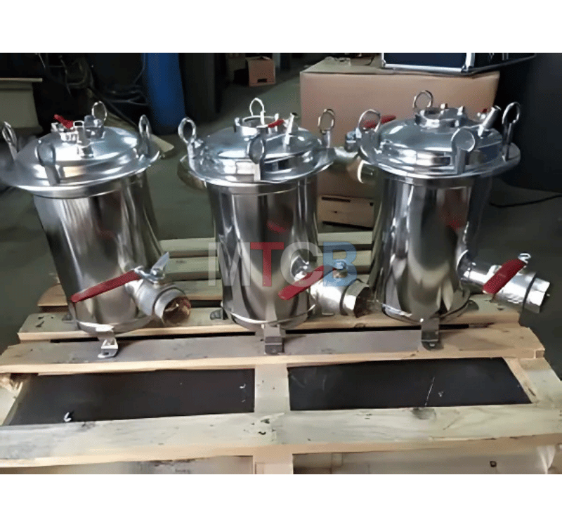 Trois filtres vapeur alimentaires industriels cylindriques en acier inoxydable brillant, avec couvercles amovibles et vannes rouges, posés sur une palette en bois.