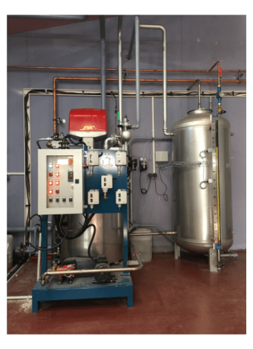 Chaudière à vapeur vapeur industrielle bleu avec un brûleur rouge, un panneau de commande électrique et un réservoir en acier inoxydable, installé dans une salle technique avec des conduites de vapeur et d’eau.